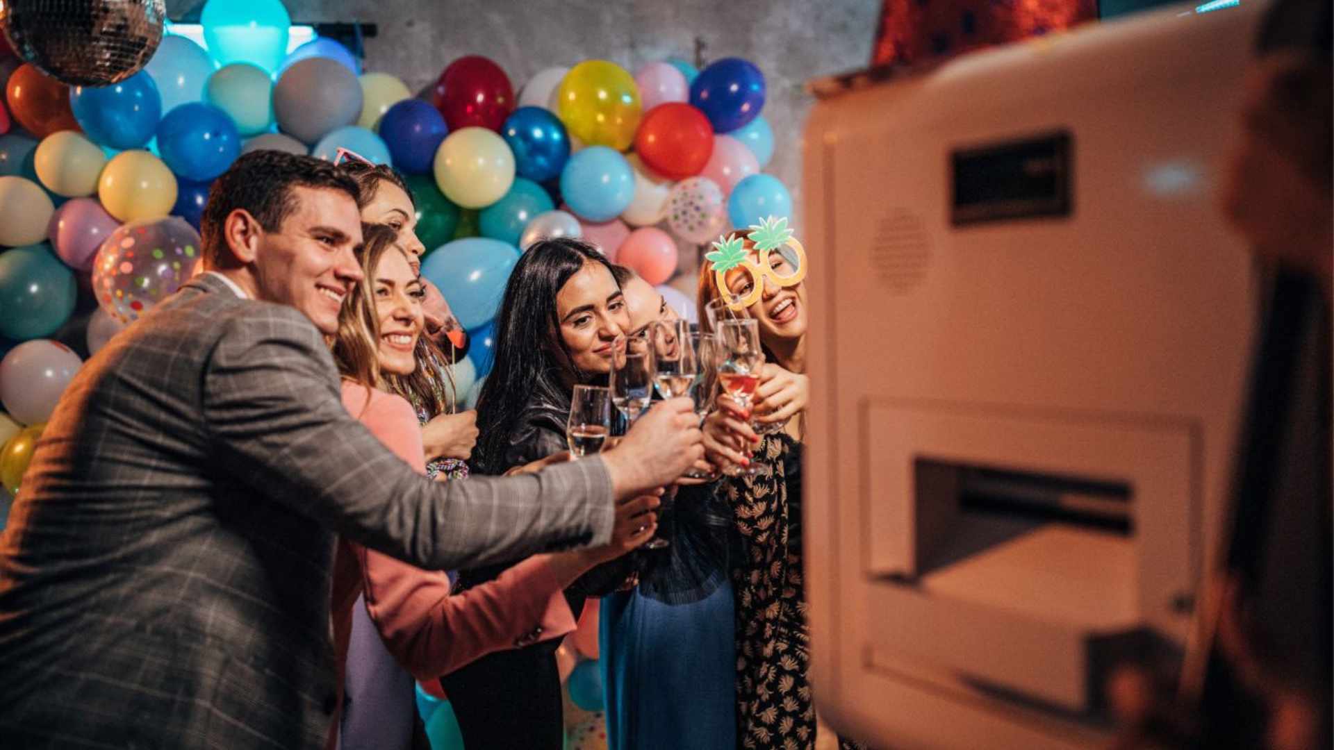 Group in photo booth with balloons in background